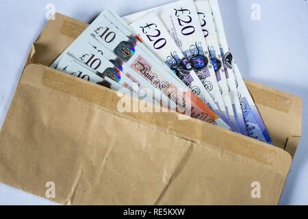 Busta marrone farcite con inglese dieci e venti pound note. Foto Stock