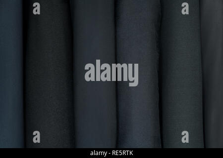 Abbigliamento diverse texture di panno fine presso un negozio di sartoria. Abbigliamento design. Dark, vestiti di nero Foto Stock