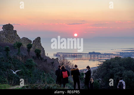 Hastings, East Sussex, Regno Unito. Il 20 gennaio 2019. Walkers ben avvolto fino a guardare il tramonto dal castello di Hastings alla fine di una fredda giornata di sole. Foto Stock