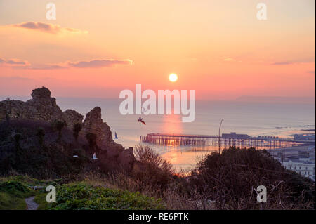 Hastings, East Sussex, Regno Unito. Il 20 gennaio 2019. Gabbiani volano dal castello al tramonto verso il molo alla fine di una tranquilla chiara giornata di sole. Foto Stock