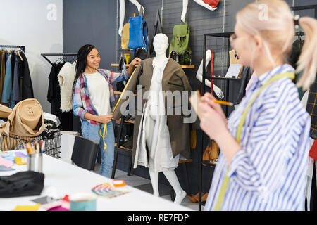 I giovani di adattare le misurazioni da spalmare sul manichino e a parlare con il suo collega nelle vesti di officina Foto Stock