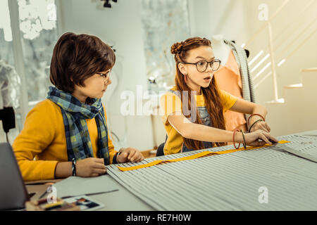 I Capelli rossi ragazza avente molte idee creative mentre disegnare vestiti Foto Stock