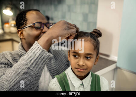 Afro-americano di padre rendendo l'acconciatura per la sua giovane figlia Foto Stock