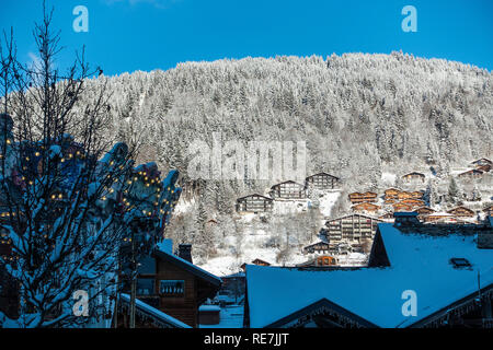 Sistemazioni in stile chalet nella neve con i boschi di pini sul pendio di una collina in Morzine Haute Savoie Portes du Soleil Francia Foto Stock