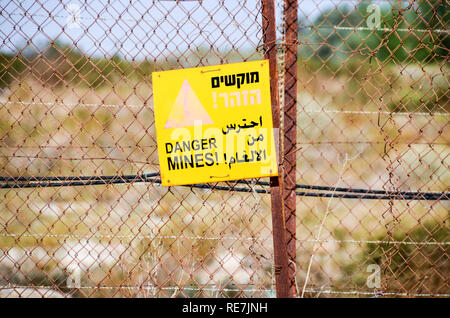 'Drabbia mine' firmare in Israele/Cisgiordania Palestina, con filo spinato e disclaimer in arabo ed ebraico, a fronte di una struttura abbandonata Foto Stock