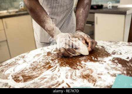 Close up di afro-americano di uomo impastare la pasta per torta Foto Stock