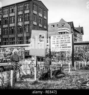 Agosto 1986, donna e ragazzo, lasciando il settore americano segno di avvertimento, il muro di Berlino graffitis, Zimmerstrasse street, Berlino Ovest lato, Germania, Europa Foto Stock