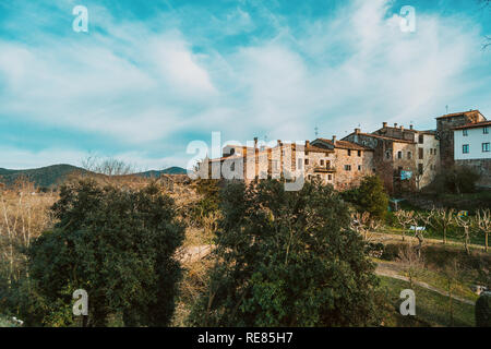 Vista di alcune case di un borgo medievale accanto ad alcuni alberi dalla periferia Foto Stock