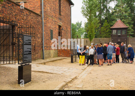 Oswiecim, Polonia - 11 luglio 2018. I visitatori del campo di concentramento di Auschwitz si affollano intorno ascoltando i loro tour guida Foto Stock
