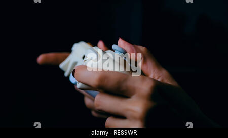 Giovani femmine gamer con il gamepad o joystick la riproduzione del video gioco in camera oscura. Giochi, divertimento, il tempo libero e il concetto di intrattenimento Foto Stock