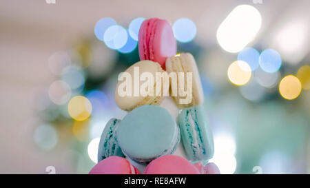 Macaron tower - multicolore di gustosi amaretti francese con Natale bokeh ghirlanda luminosa. Cucina francese, candy, vacanze, anno nuovo e il concetto di cibo Foto Stock