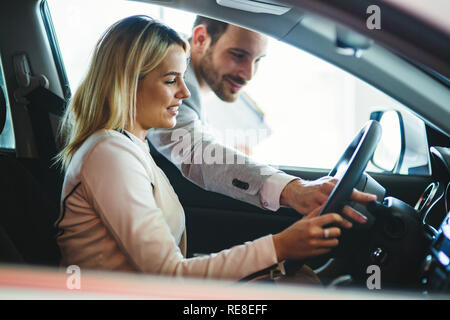 La donna sta parlando di bello concessionaria auto lavoratore durante la selezione di un automobile Foto Stock