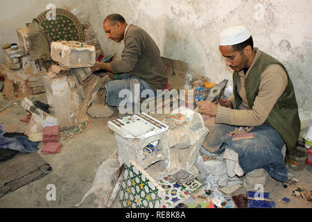 Artigiani rendendo piastrella Mosaico pezzi in ceramica co-operativa in Fez, in Marocco Foto Stock