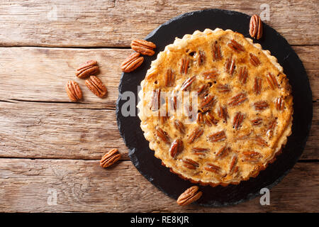 Gustosa torta alle noci pecan con cannella e caramello close-up su una scheda di ardesia sul tavolo. Parte superiore orizzontale vista da sopra Foto Stock