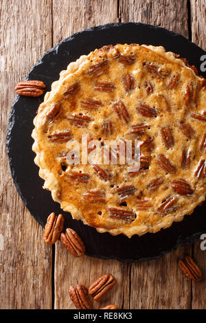 Sud Americana pecan tart close-up su una scheda di ardesia sul tavolo. Verticale in alto vista da sopra Foto Stock