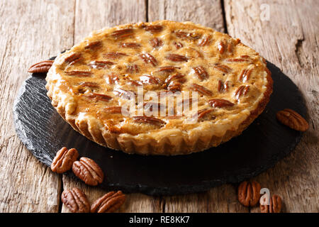 Gustosa torta alle noci pecan con cannella e caramello close-up su una scheda di ardesia sul tavolo orizzontale. Foto Stock