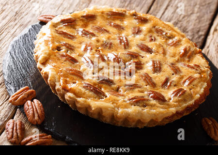 Noci pecan tagliate a dessert crostata con cannella e caramello close up su una scheda di ardesia sul tavolo orizzontale. Foto Stock