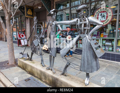 ASHEVILLE, NC, Stati Uniti d'America-1/18/19: lo Shopping Daze scultura di metallo in piedi di fronte a Malaprops Bookstore, con un banjo-playing busker visibile dietro il Foto Stock