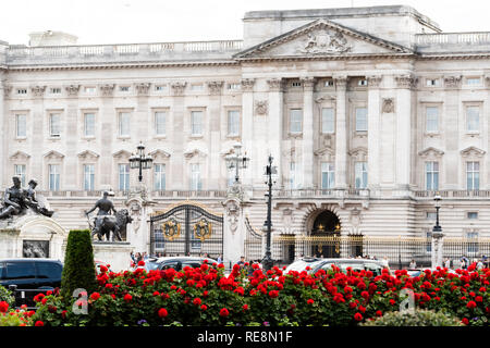 London, Regno Unito - 21 Giugno 2018: Palazzo di Buckingham Gate recinzione edificio di architettura durante il giorno di estate con le automobili nel traffico e Red Rose fiore g paesaggistici Foto Stock