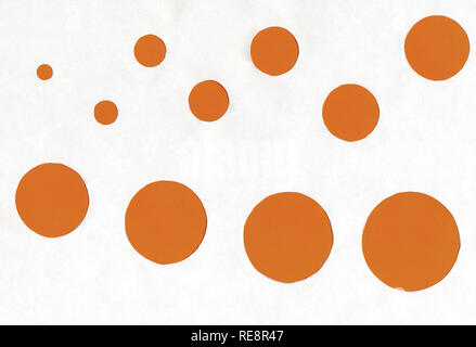 Piccoli e grandi cerchi di colore arancione su sfondo bianco. Foto Stock
