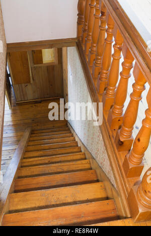 Ringhiera in legno di pino e scalinata che conduce al piano terra all'interno di una vecchia casa in stile anni '1807. Foto Stock