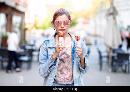 Ragazza con i capelli rosa in denim suit mangiare deliziosi gelati su sfondo della città Foto Stock