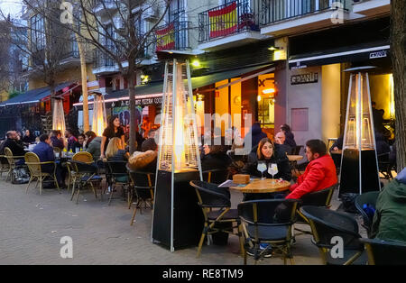 Persone a tavoli all'esterno su una fredda notte invernale in un cafe in Alameda de Hercules a Siviglia, Spagna Foto Stock