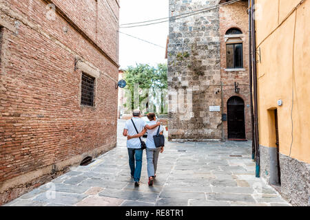 Chiusi, Italia - 25 agosto 2018: Alley Street nel piccolo villaggio di città in Umbria durante il giorno con gente giovane holding hands abbracciando la deambulazione dalla colorfu Foto Stock