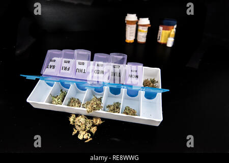 La marijuana medica sulla tavola nera con farmaci farmaceutici in background Foto Stock