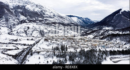 Vista aerea della bella coperta di neve villaggio di Opi con montagne innevate sullo sfondo. Foto Stock