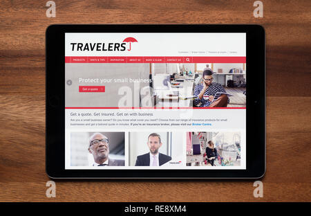 Il sito web di viaggiatori business assicurativo è visto su un tablet iPad, il quale è appoggiato su un tavolo di legno (solo uso editoriale). Foto Stock