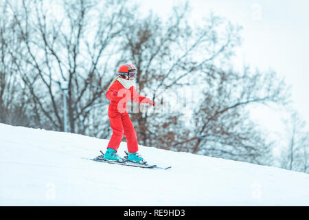 LVIV, Ucraina - 12 Gennaio 2019: boy sciare giù dalla collina in rosso cappotto. attività invernali. Foto Stock