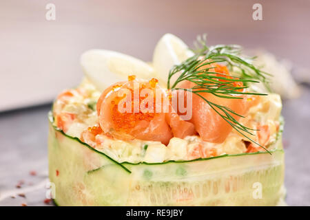 Insalata con salmone avvolto con fette di cetriolo. Round insalata con salmone e cavair close up. Foto Stock