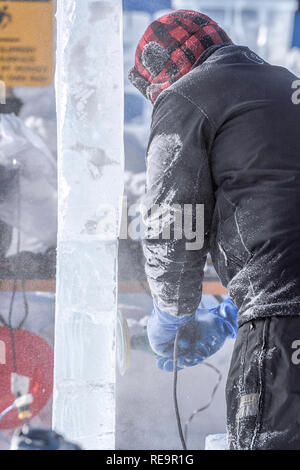 Scultore di ghiaccio utilizzando una smerigliatrice elettrica per lucidare una lastra di ghiaccio presso il Lago Louise Ice Magic Festival nel Parco Nazionale di Banff, Alberta Canada Foto Stock