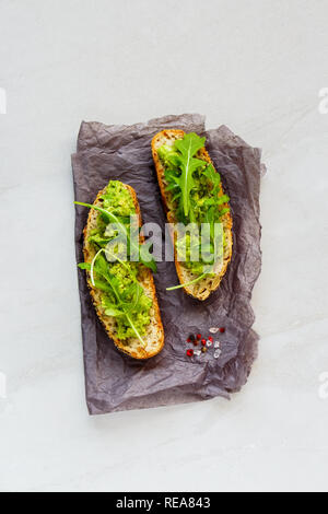 Vegan toast con avocado e rucola laici piana. Buona grassi materie mangiare sano concetto. Foto Stock