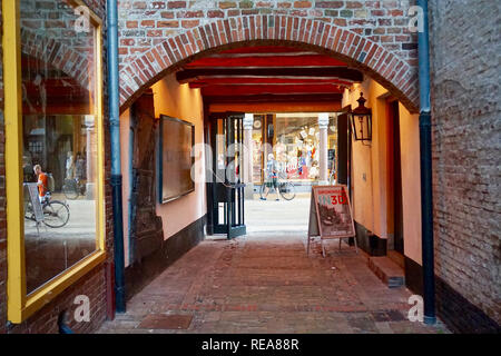 Groningen, Paesi Bassi: Nord del museo di spedizione. Del Medioevo europeo vicolo di mattoni tunnel con un ingresso ad arco, portando ad una strada dello shopping. Foto Stock