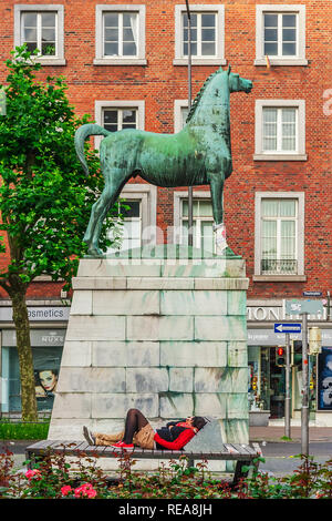 Statua di un cavallo in piazza del teatro di Aquisgrana, giovani stanno dormendo sul banco, Germania Foto Stock