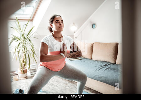 Dai capelli scuri donna concentrato che soggiornano in orante la postura Foto Stock