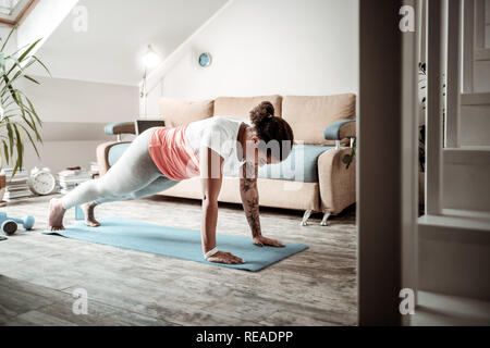 Concentrato giovane lady facendo push-up durante il corso di formazione Foto Stock