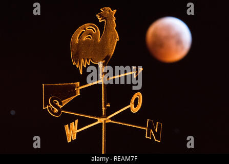 Laatzen, Germania. Xxi gen, 2019. Oscurano la luna piena appare come una cosiddetta "sangue luna" e appare di colore rossastro - fotografato dietro un segnavento sul tetto di una casa. La luna, il sole e la terra sono esattamente in una linea durante un'eclisse lunare. Credito: Julian Stratenschulte/dpa/Alamy Live News Credito: dpa picture alliance/Alamy Live News Foto Stock