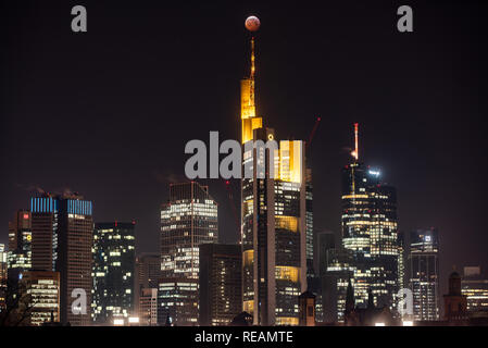 21 gennaio 2019, Assia, Frankfurt/Main: Come un rosso, cosiddetto "sangue luna", la luna piena sorge sopra i grattacieli di Francoforte e la Commerbank (M) sede, mentre passi nell'ombra della Terra. L'ombra dell'anima copre la superficie visibile della luna. La luna, il sole e la terra sono esattamente in linea. Foto: Frank Rumpenhorst/dpa Credito: dpa picture alliance/Alamy Live News Foto Stock