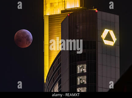 21 gennaio 2019, Assia, Frankfurt/Main: Come un rosso, cosiddetto "sangue luna", la luna piena sorge accanto al giallo illuminato sede Commerbank, mentre passi nel core ombra della Terra. L'ombra dell'anima copre la superficie visibile della luna. La luna, il sole e la terra sono esattamente in linea. Foto: Frank Rumpenhorst/dpa Credito: dpa picture alliance/Alamy Live News Foto Stock