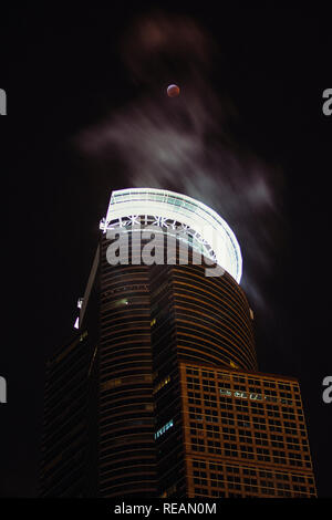 20 gennaio 2019 - Minneapolis, Minnesota, Stati Uniti d'America - centro di Minneapolis Capella torre con la luna piena passando attraverso le eclissi lunare totale come edifici limitrofi di sfiato passa a vapore. Foto Stock