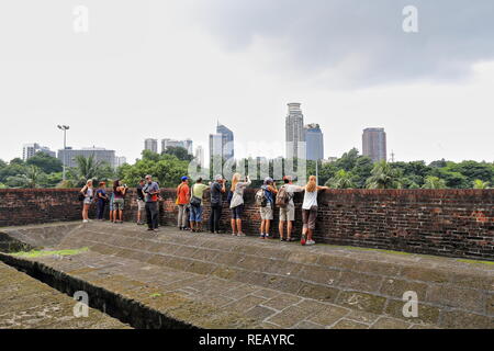 Manila, Philippines-October 24, 2016: turisti ammirare lo skyline urbano come si vede dal tetto del Ravelin di Porta Reale fuori dalla parete di tamponamento di Foto Stock