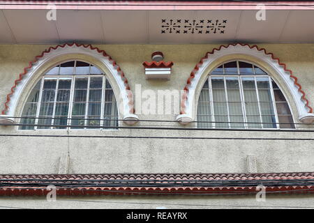 Coppia di vetrata finestre ad arco-stile Art Deco decorazione sulla facciata di un ufficio commerciale edificio all'angolo NE del generale Luna e strade reale Foto Stock