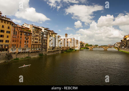 Ginnastica mattutina - un lone rematore righe lungo il fiume Arno in una bella mattina d'estate. Ponte Vecchio oltre il Fiume Arno. Firenze, Italia Foto Stock