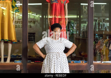 Durban, Sud Africa - Gennaio 07th, 2019: un nero donna africana che è designer di moda, posa indossando un abito con punti nella parte anteriore del suo store. Foto Stock