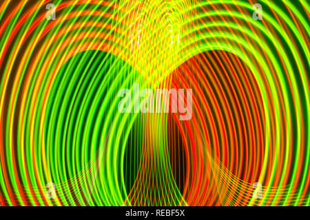 Abstract rainbow neon incandescente linee di attraversamento pattern. Sfondo scuro di luci al neon colorate di giallo, orabge e incandescente verde forme di luce. Foto Stock