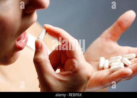 Giovane donna assumendo compresse, capsule Foto Stock