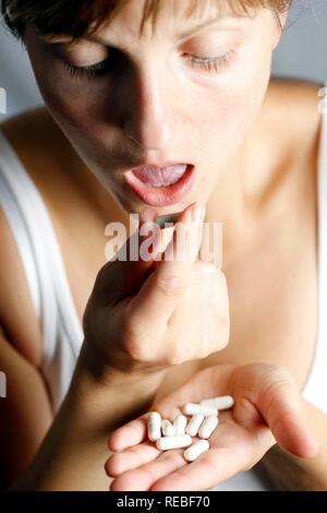 Giovane donna assumendo compresse, capsule Foto Stock
